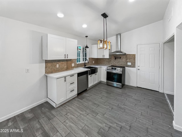 kitchen with pendant lighting, wall chimney exhaust hood, white cabinetry, and stainless steel appliances