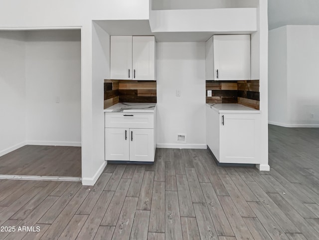 kitchen with white cabinets, backsplash, and light hardwood / wood-style flooring