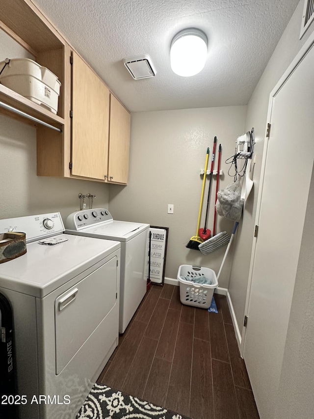 laundry area with washing machine and dryer, a textured ceiling, and cabinets