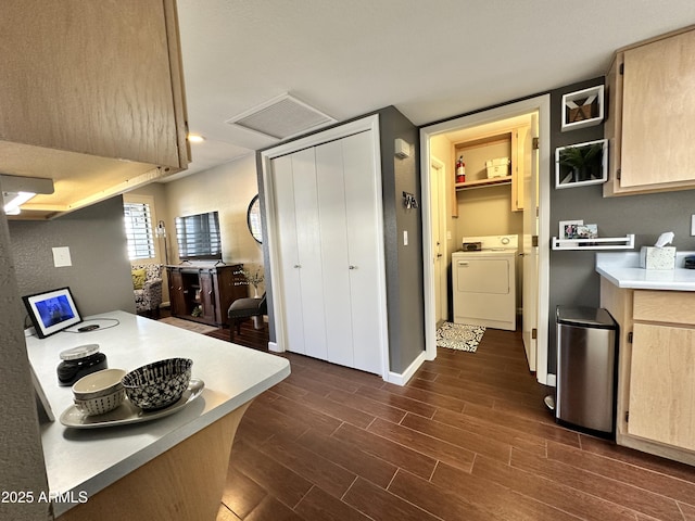 kitchen with dark wood-type flooring, washer and dryer, and light brown cabinets