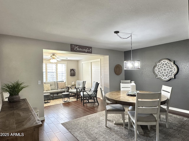 dining area with ceiling fan with notable chandelier and a textured ceiling