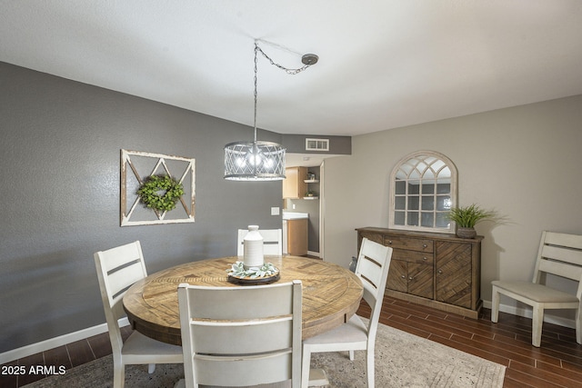 dining room with dark hardwood / wood-style flooring and an inviting chandelier