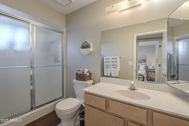 bathroom with toilet, a shower with door, and vanity