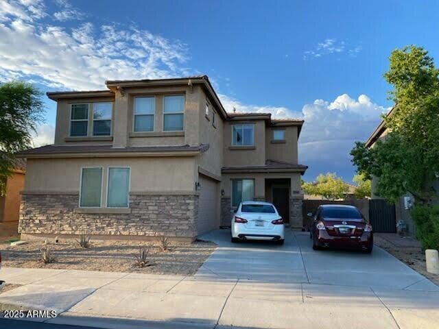 view of front of house with stone siding, driveway, and stucco siding