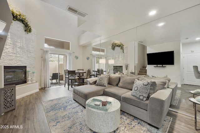 living room with a large fireplace, wood-type flooring, and a high ceiling