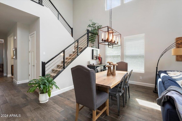 dining space with a wealth of natural light, dark hardwood / wood-style floors, and a towering ceiling