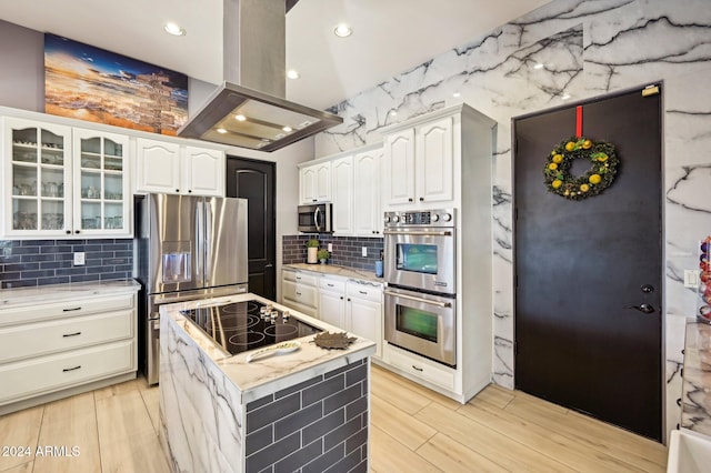 kitchen with appliances with stainless steel finishes, island range hood, a center island, light hardwood / wood-style floors, and white cabinetry