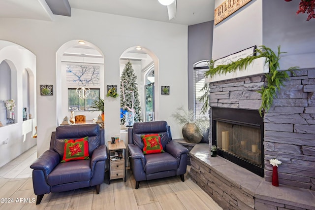 living area featuring light wood-type flooring and a stone fireplace