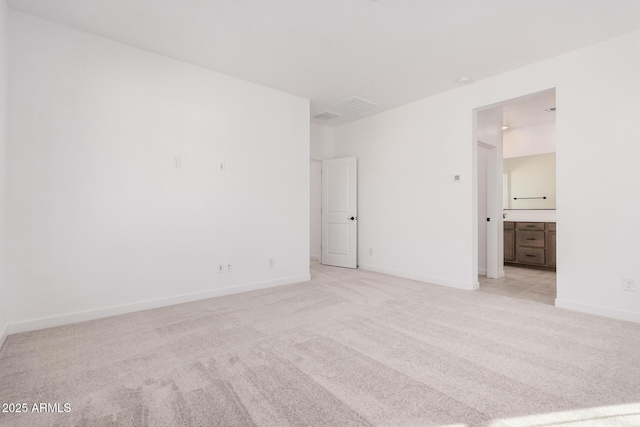 unfurnished bedroom featuring light colored carpet and connected bathroom