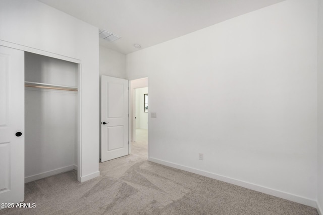 unfurnished bedroom featuring light carpet and a closet