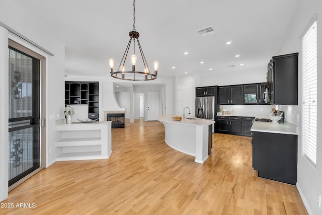 kitchen with light wood finished floors, light countertops, dark cabinets, open floor plan, and visible vents