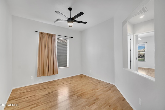 spare room featuring baseboards, ceiling fan, visible vents, and wood finished floors