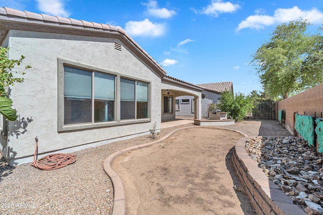 exterior space featuring a tiled roof, a fenced backyard, and stucco siding