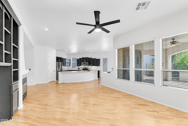 unfurnished living room featuring baseboards, ceiling fan, light wood finished floors, and visible vents
