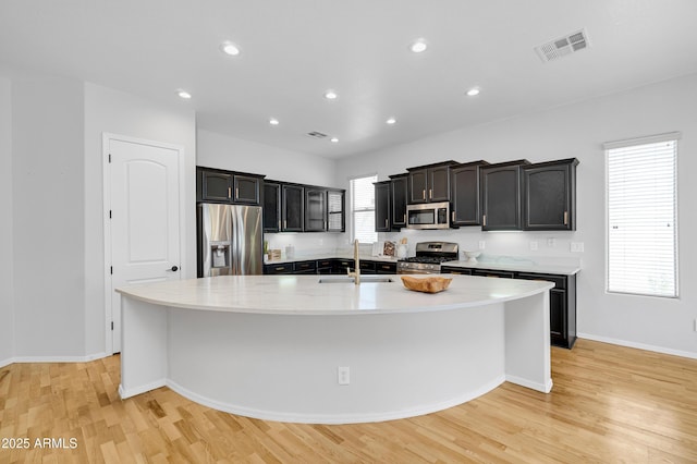 kitchen featuring a sink, appliances with stainless steel finishes, light wood-style floors, and visible vents