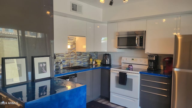 kitchen featuring tasteful backsplash, visible vents, white cabinets, stainless steel appliances, and a sink