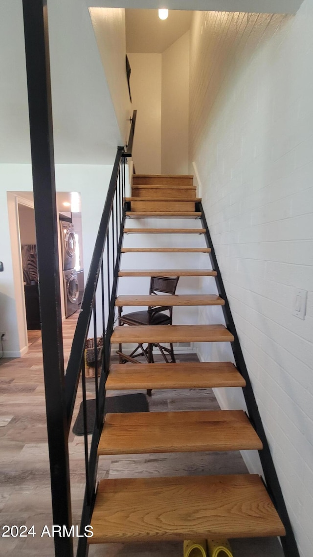 staircase featuring brick wall, washer / clothes dryer, and wood finished floors