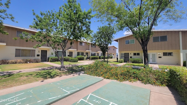 view of home's community with shuffleboard and a lawn