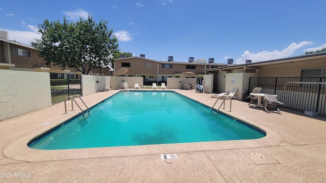 pool with a patio area and fence