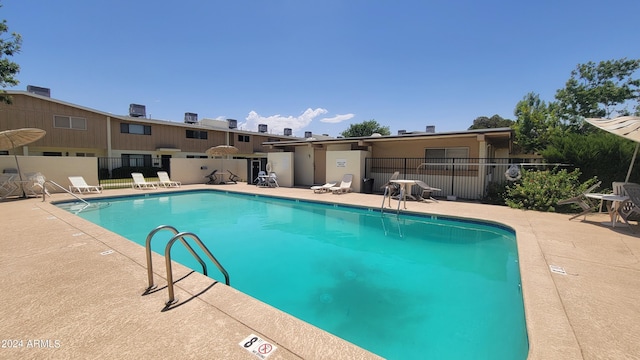 community pool with a patio area and fence