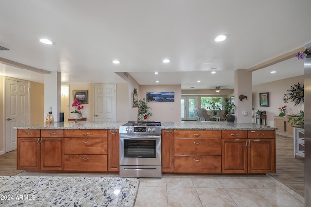 kitchen with stainless steel electric stove, light stone countertops, ceiling fan, and light tile patterned flooring