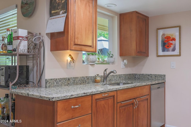 kitchen with light stone counters, sink, and stainless steel dishwasher