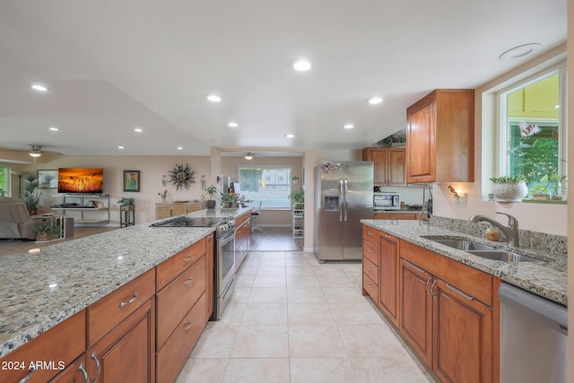 kitchen featuring light stone countertops, appliances with stainless steel finishes, light tile patterned floors, and sink