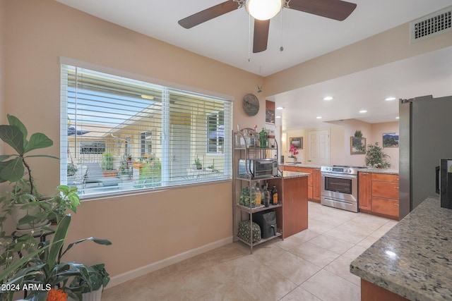 kitchen featuring ceiling fan, light stone countertops, appliances with stainless steel finishes, light tile patterned flooring, and kitchen peninsula