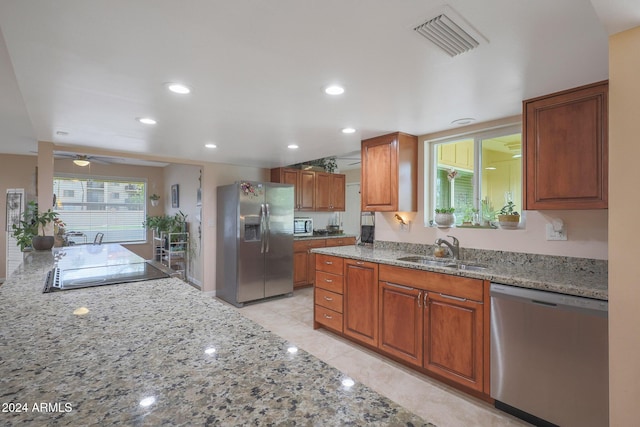 kitchen with light stone countertops, stainless steel appliances, and sink