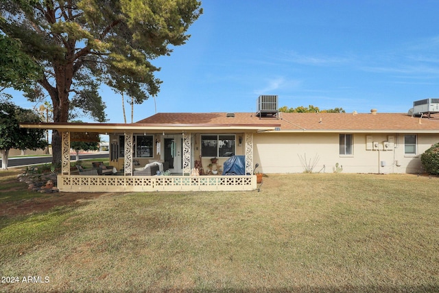 back of property featuring covered porch, a yard, and central AC