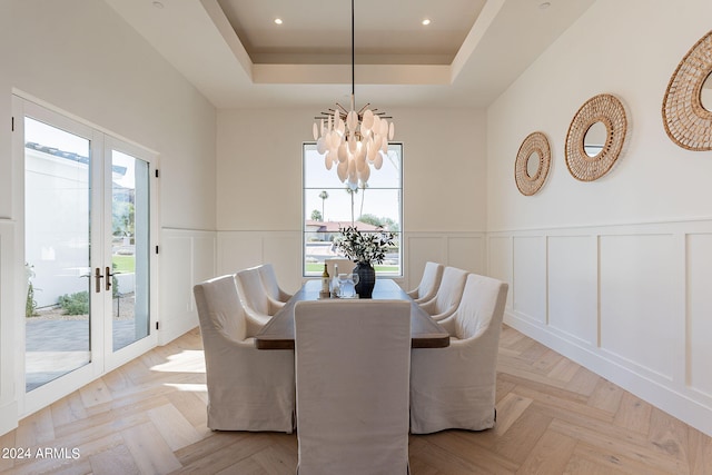 dining room featuring a chandelier, french doors, a tray ceiling, and light parquet floors