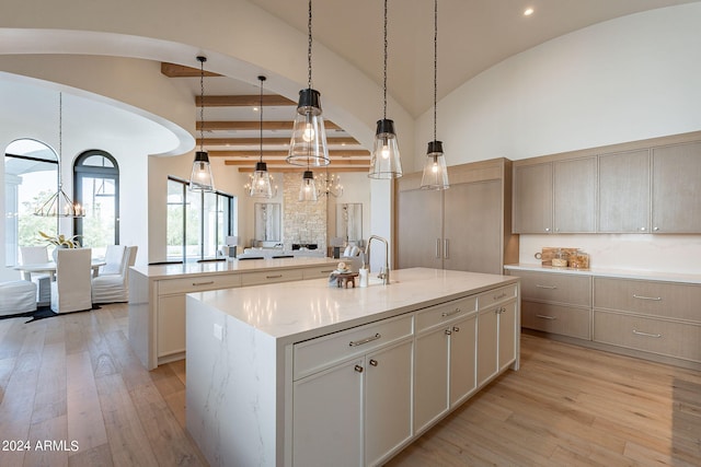 kitchen with light stone countertops, a spacious island, light hardwood / wood-style flooring, a fireplace, and hanging light fixtures