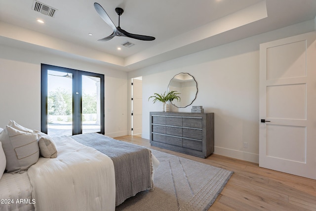 bedroom featuring access to outside, light hardwood / wood-style flooring, a raised ceiling, and ceiling fan