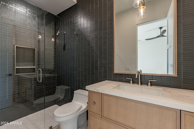 bathroom with vanity, ceiling fan, toilet, tile walls, and a shower with shower door