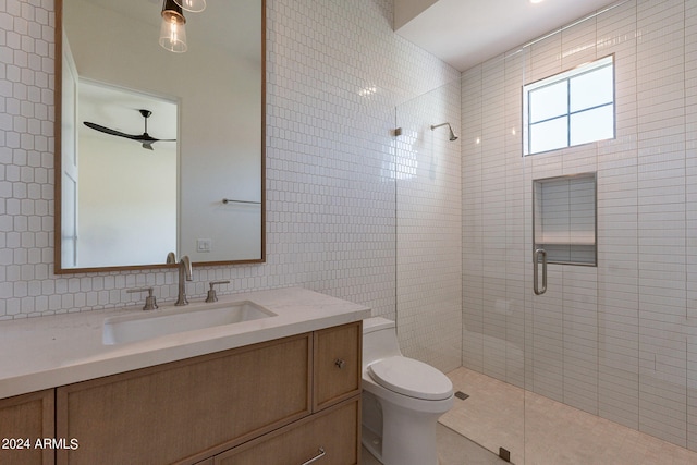 bathroom with ceiling fan, an enclosed shower, toilet, vanity, and tile walls