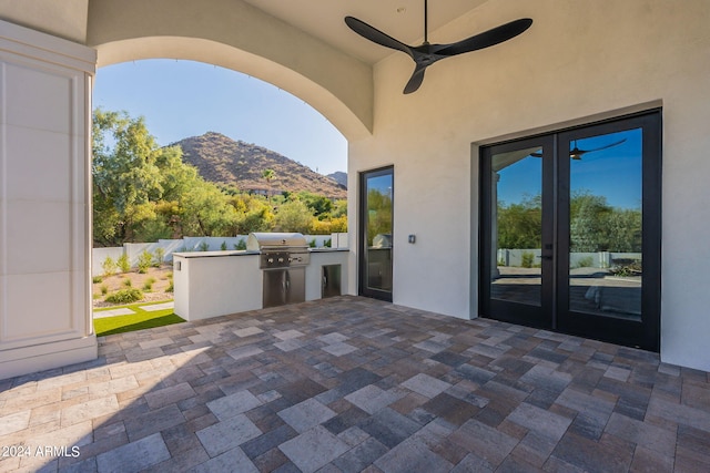 view of patio / terrace with a mountain view, french doors, ceiling fan, a grill, and exterior kitchen