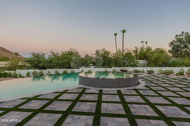 pool at dusk featuring a patio area