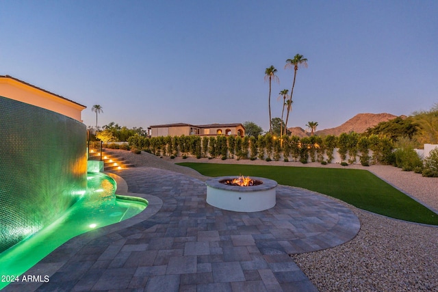 yard at dusk with a fire pit, a mountain view, and a patio area