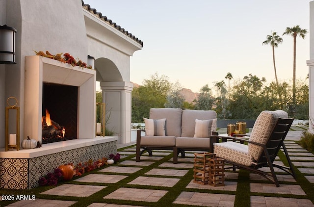 patio terrace at dusk featuring an outdoor living space with a fireplace