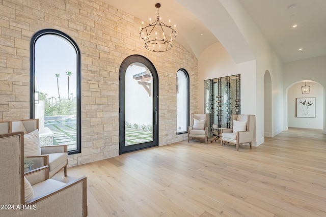 interior space featuring light hardwood / wood-style flooring, a towering ceiling, and a notable chandelier