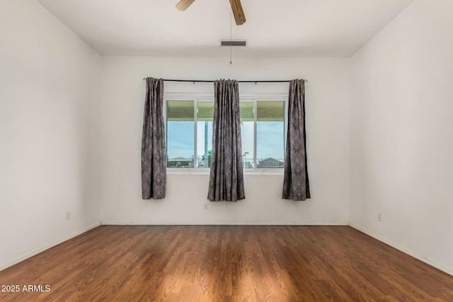 empty room with baseboards, ceiling fan, visible vents, and wood finished floors