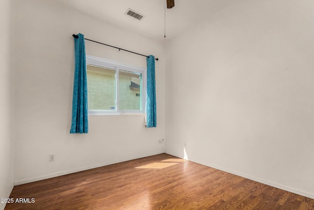 unfurnished room with a ceiling fan, wood finished floors, and visible vents