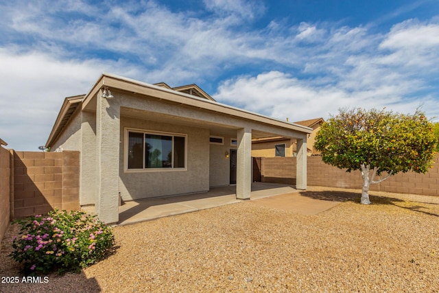 view of front of house featuring a fenced backyard, stucco siding, and a patio area