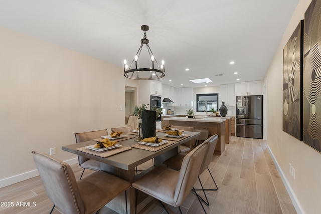 dining space with light hardwood / wood-style flooring and a notable chandelier