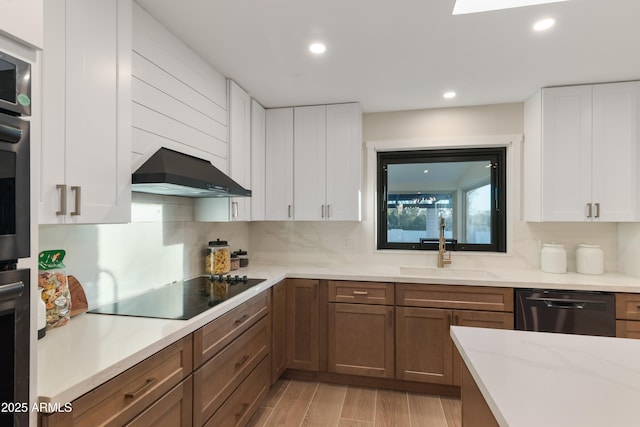 kitchen featuring black appliances, sink, light stone counters, white cabinetry, and extractor fan