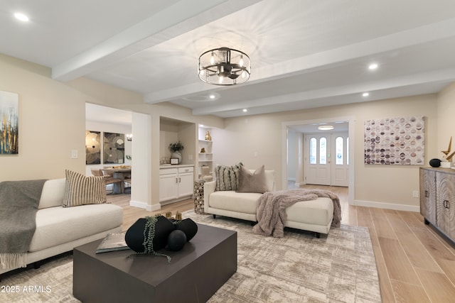 living room featuring beam ceiling, light hardwood / wood-style flooring, and an inviting chandelier