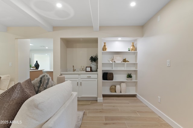 bar with beamed ceiling, white cabinetry, and sink