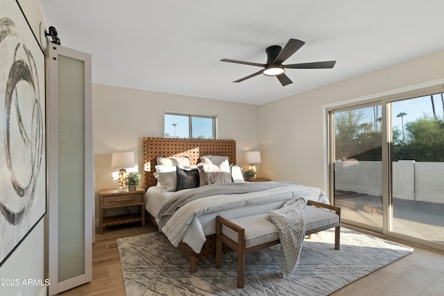 bedroom featuring access to outside, a barn door, and ceiling fan