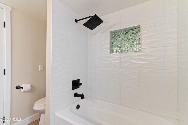 bathroom featuring tiled shower / bath combo and toilet