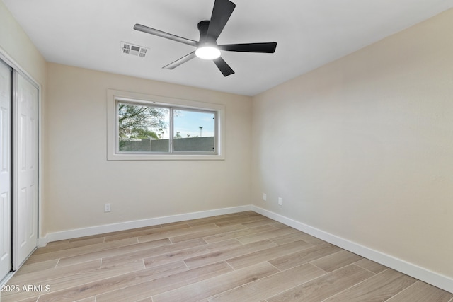 unfurnished bedroom featuring ceiling fan, a closet, and light wood-type flooring